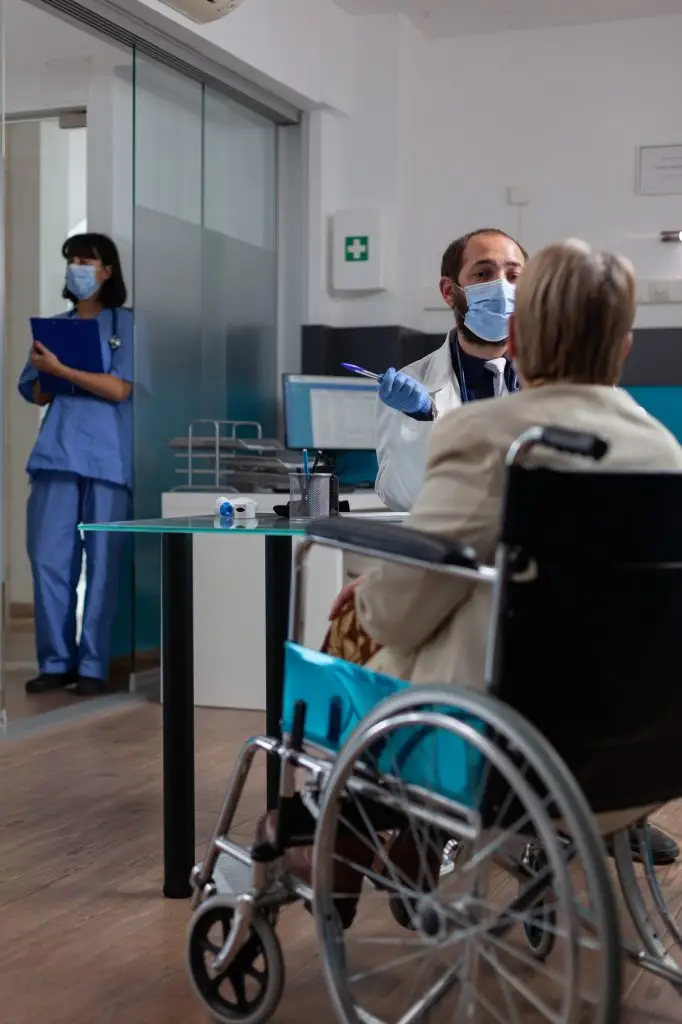 Physician meeting with old patient in wheelchair at checkup