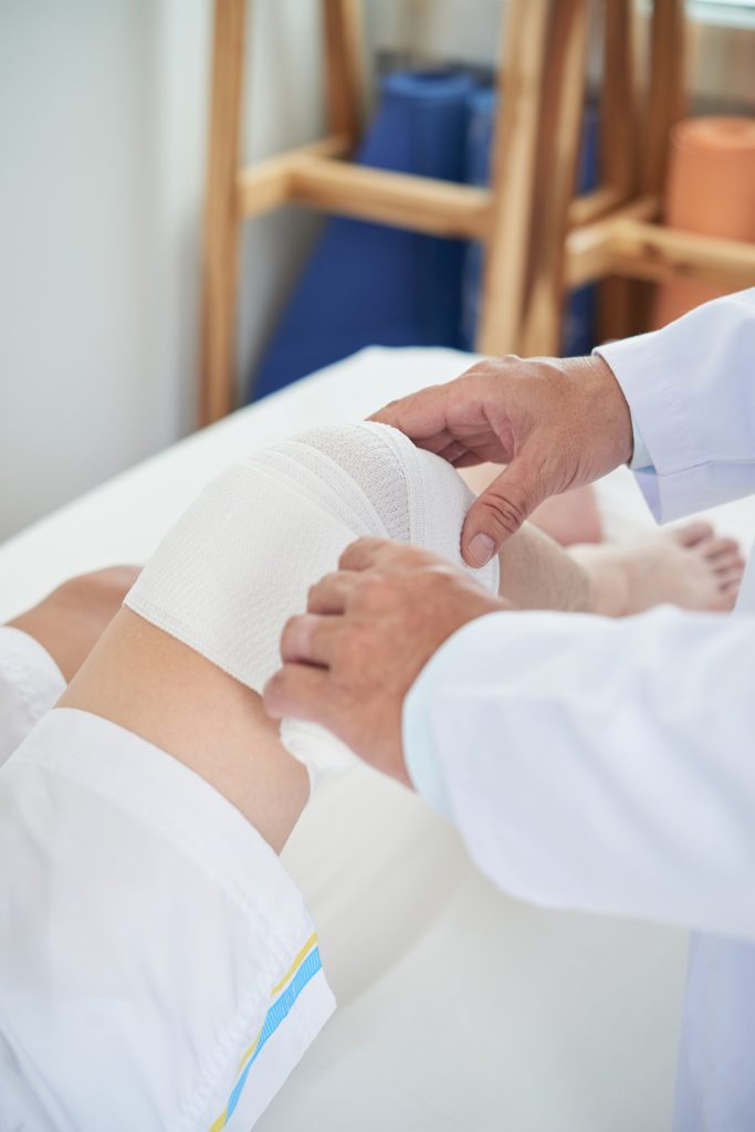 Anonymous doctor bandaging leg of patient
