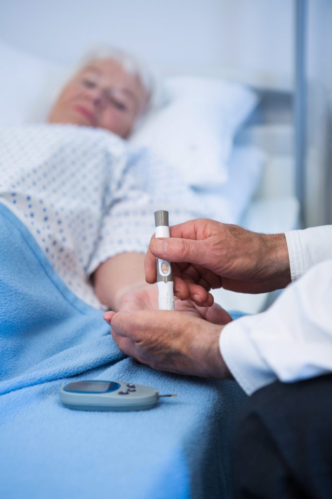 Doctor testing diabetes of senior patient with insulin pen